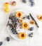 Peaches, nectarines, grapes, figs on white plate, cutlery on white tablecloth