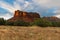 The peak of Courthouse Butte illuminated by sunset under a sky of swirling white clouds