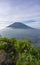 The peak of Mount Merbabu as seen from Mount Telomoyo with vegetation and trees as the foreground