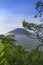 The peak of Mount Merbabu as seen from Mount Telomoyo with vegetation and trees as the foreground