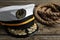 Peaked cap with accessories and rope on wooden background, closeup