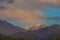 Peaks and slopes of the mountains of the Trans-Ili Alatau under thunderclouds during sunset.