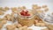 Peanut butter in a glass jar with metal fastening on a white table close-up with a bunch of nuts inside the can and outside