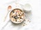 Peanut butter granola with milk, apples and blueberries - healthy energy breakfast or snack on a light background, top view