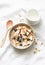 Peanut butter granola with milk, apples and blueberries - healthy energy breakfast or snack on a light background, top view.