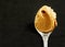 Peanut butter in spoon over black background