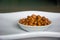 Peanuts in ceramic white bowl on wooden background