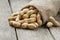 Peanuts in a miniature burlap bag on old, gray wooden surface