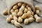 Peanuts in a miniature burlap bag on old, gray wooden surface