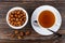 Peanuts in sugar in bowl, tea, spoon on saucer on dark table. To