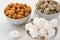 Peanuts in sugar, peanuts sprinkled with sesame seeds and peeled peanuts lies in three white bowls on a white wooden background