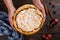 Pear pie with cream in female hands, homemade pastries on wooden table, with spices. Copy space