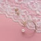 Pearl golden bracelet and stud earrings on white textile on pink background