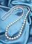 Pearl necklace on turquoise silk fabric