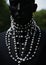 Pearl necklaces in men's fashion. A guy in a black suit and with a string of natural pearls around his neck.