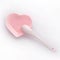 Pearlescent pink ceramic saucer in the form of a heart and a spoon in a plate on a white background. Toning. Modern glossy dishes