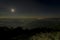 Pearls of light of Queen of Hills, Darjeeling town, at night at far right. Full moon on the night sky shows of mountains of