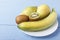 Pears, banana and kiwi fruit on white plate. Healthy breakfast or dinner with natural ripe fruits on wooden table. Side view. Copy