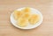 Pears halves on a white plate atop wood table