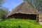 Peasants hut. Country house on spring landscape. Old village cottage. Building made of wood with thatched roof
