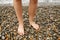 Pebble beach. Bare feet stand on round pebbles