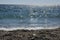 Pebble beach with blue sea and waves with sun reflections