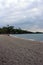 The pebble beach and shoreline of Anaehoomalu Bay, Hawaii, with Palm trees at the far end of the beach