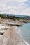 Pebble beach with stone ledges, sun loungers, umbrellas and a small restaurant