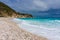 Pebble beach, stormy blue sea, green hill and gray sky in Dominican Republic