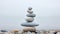 Pebble cairn, stack of smooth pebbles on the seaside. Stone stack on the beach near a calm misty ocean. Generative AI