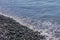 Pebble coastline. Seashore  with transparent water and small stones