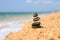 A pebble pyramid stands on a shell shore next to the sea. Sea wave next to the tower.