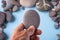 Pebble stone hold in hand on blue background with pebbles