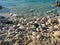 Pebble stones on the shore close up in the blurry sunset light in the distance background