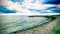 Pebbles beach and breakwater with cloudy sky