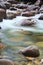 Pebbles in creek flowing water