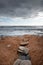 Pebbles on  a red wavy  beach and stormy cloudy sky