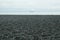 A pebbly beach leading to a silver-blue sea.