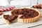 Pecan cranberry pie with slice removed on white wood