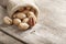 Pecans spill out of a bag on a wooden table, close-up. Peeled, in a shell