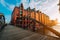 Pedestrian arch bridge over canals in the Speicherstadt of Hamburg. Warm golden hour sunset light on red bricks