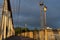 Pedestrian asphalt path on bridge over the railway tracks, left white roadway fence, right yellow bridge fence with row of lights