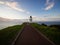 Pedestrian asphalt road walkway leading to historic white Cape Reinga lighthouse on cliff top in Northland New Zealand