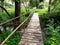 Pedestrian bridge over a stream built of wooden logs with a one-sided railing