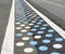 Pedestrian crosswalk on asphalt road colored with blue and white dots