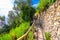 Pedestrian hiking stone path trail with railing between Corniglia and Vernazza villages with green trees, blue sky background, Nat