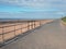 Pedestrian walkway next to the sea in crosby merseyside with distant figures on the beach on summer sunlight