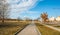 Pedestrian walkway or sidewalk pavement with park on the one side and urban traffic road on the other in the city street with blue