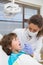 Pediatric dentist examining a little boys teeth in the dentists chair