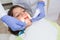 Pediatric dentist examining a little boys teeth in the dentists chair